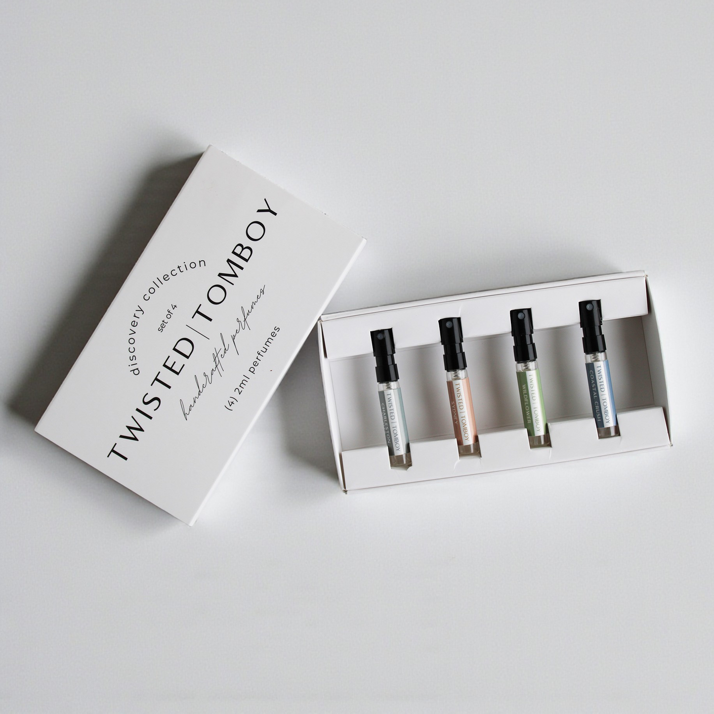 Set of perfume bottles in a box with 'Twisted Tomboy' packaging on a light gray background