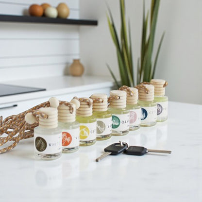 Car diffusers in various scents displayed on a countertop with decorative elements and car keys.