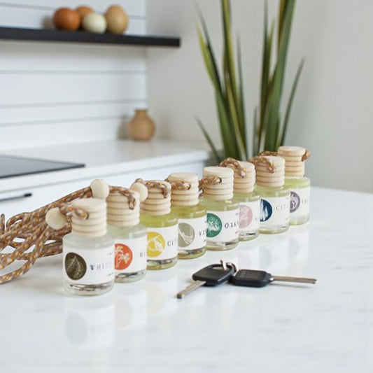 Car diffusers in various scents displayed on a countertop with decorative elements and car keys.