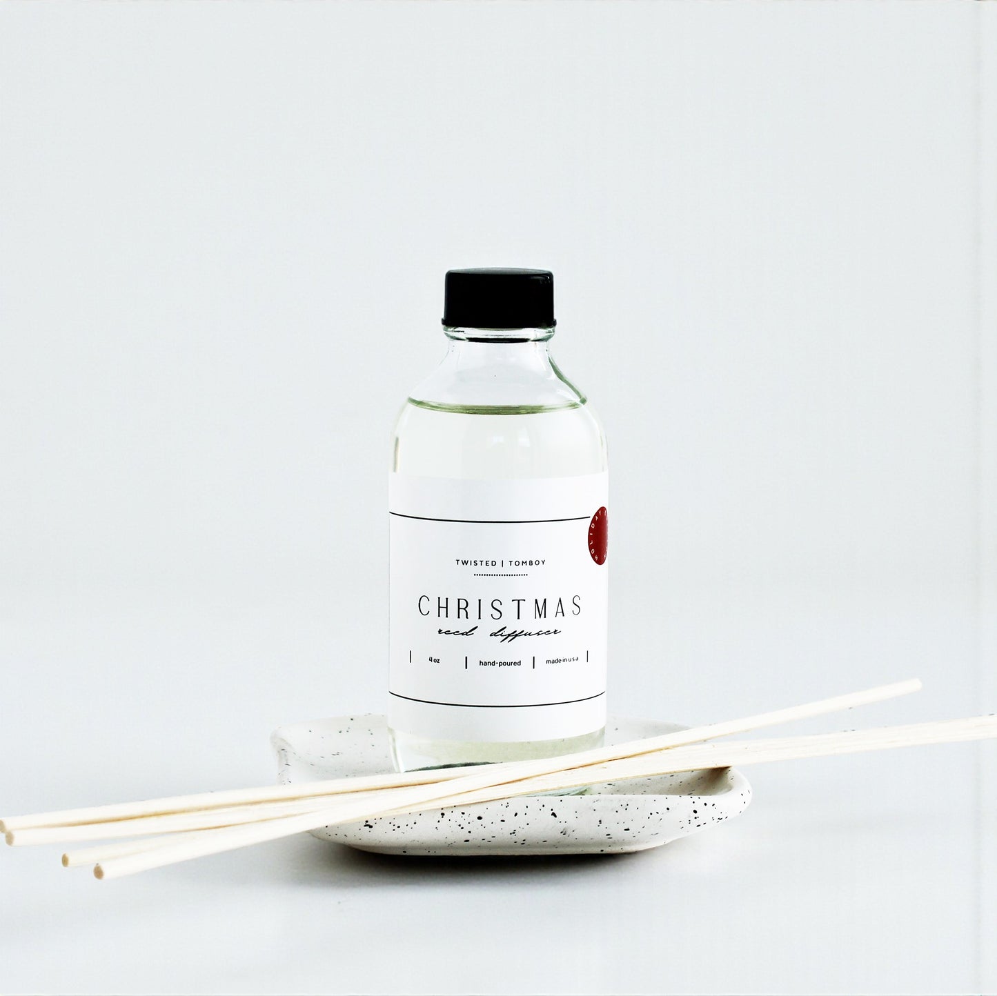 Reed Diffusers in six scents, featuring a clear bottle and natural reed sticks on a speckled dish. NEW ARRIVAL!
