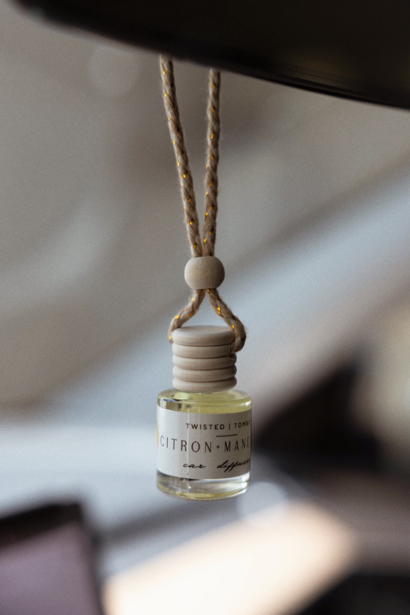 Twisted Tomboy citron and mandarin car diffuser hanging from rearview mirror