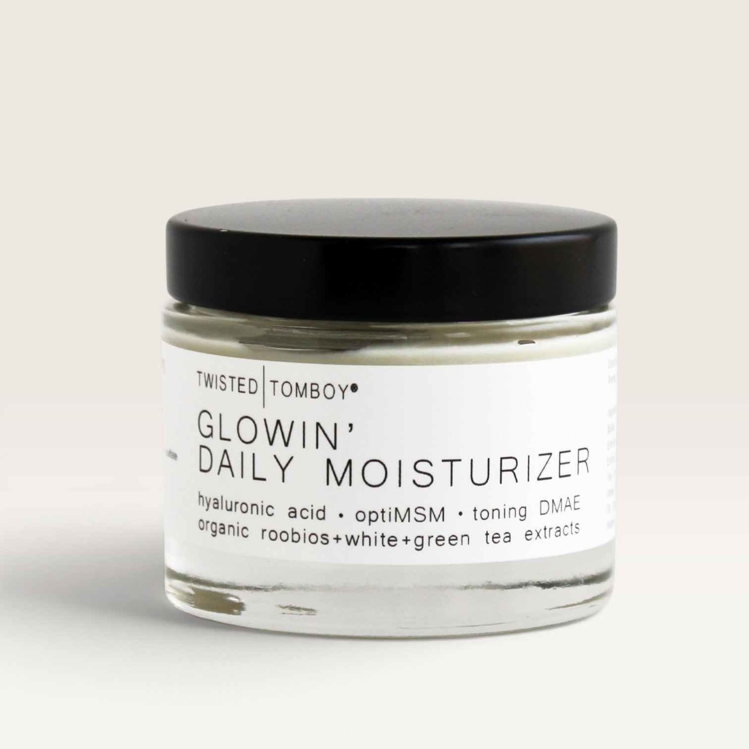 Twisted Tomboy Glowin' Daily Moisturizer in a clear glass jar with a black lid 