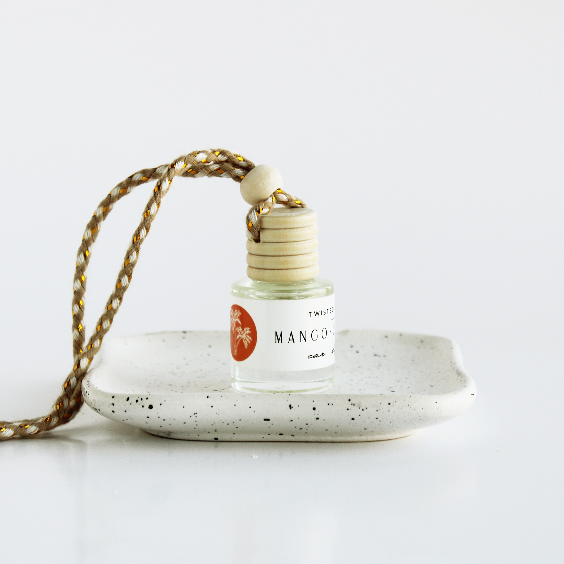 Mango+Coconut with a gold string on a speckled ceramic dish against a white background