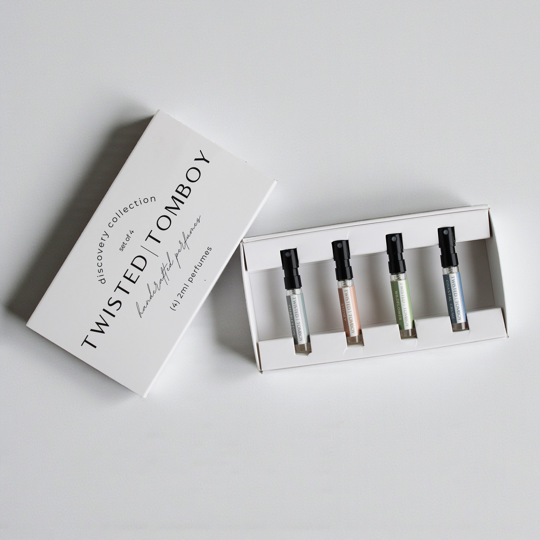 Set of perfume bottles in a box with 'Twisted Tomboy' packaging on a light gray background