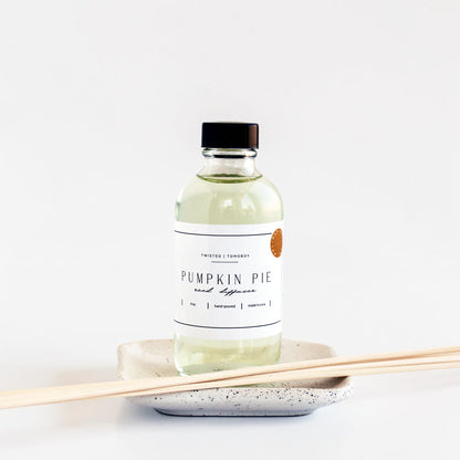 Bottle of 'Pumpkin Pie' reed diffuser bottle with reeds on a white background