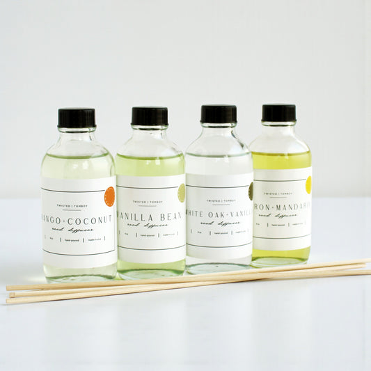 Reed diffusers in six scents including Mango-Coconut, Vanilla Bean, White Oak, and Iron-Mandarin with natural reeds.