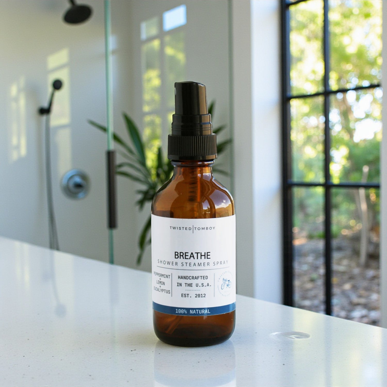 An amber glass spray bottle labeled 'BREATHE' on countertop