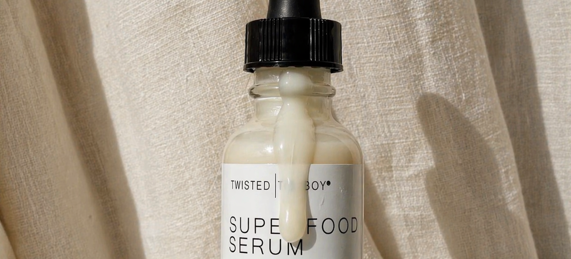 Superfood serum bottle with dropper on a beige fabric background