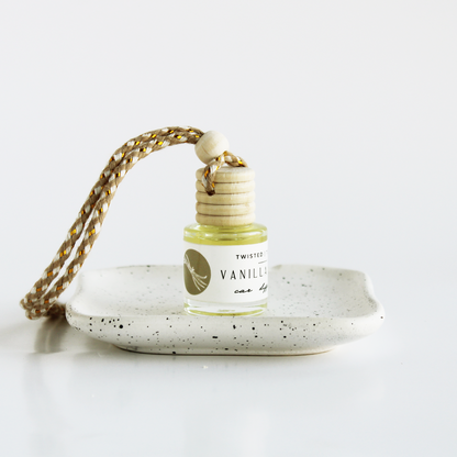 Vanilla Bean scented car air freshener on a speckled ceramic dish with a white background