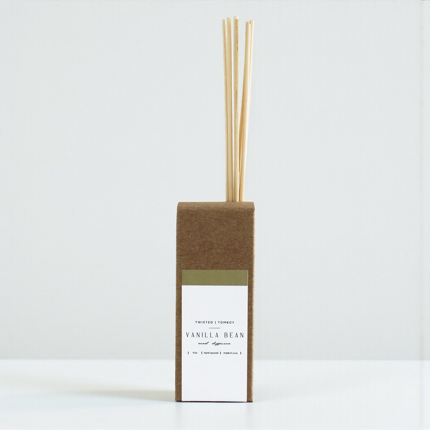 Vanilla bean diffuser with reeds in a cardboard box on a white background