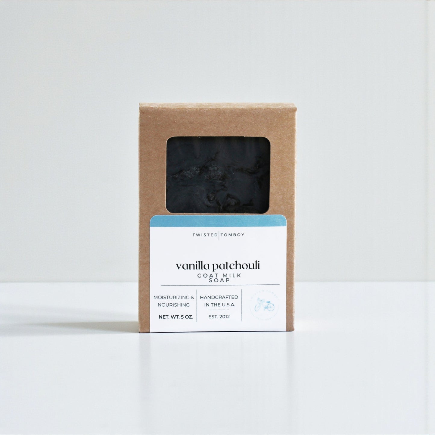 Vanilla patchouli goat milk soap in a brown cardboard box on a white background