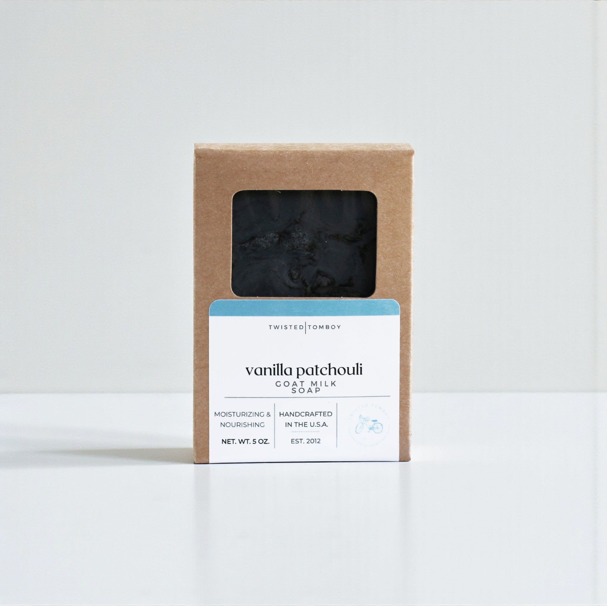 Vanilla patchouli goat milk soap in a brown cardboard box on a white background