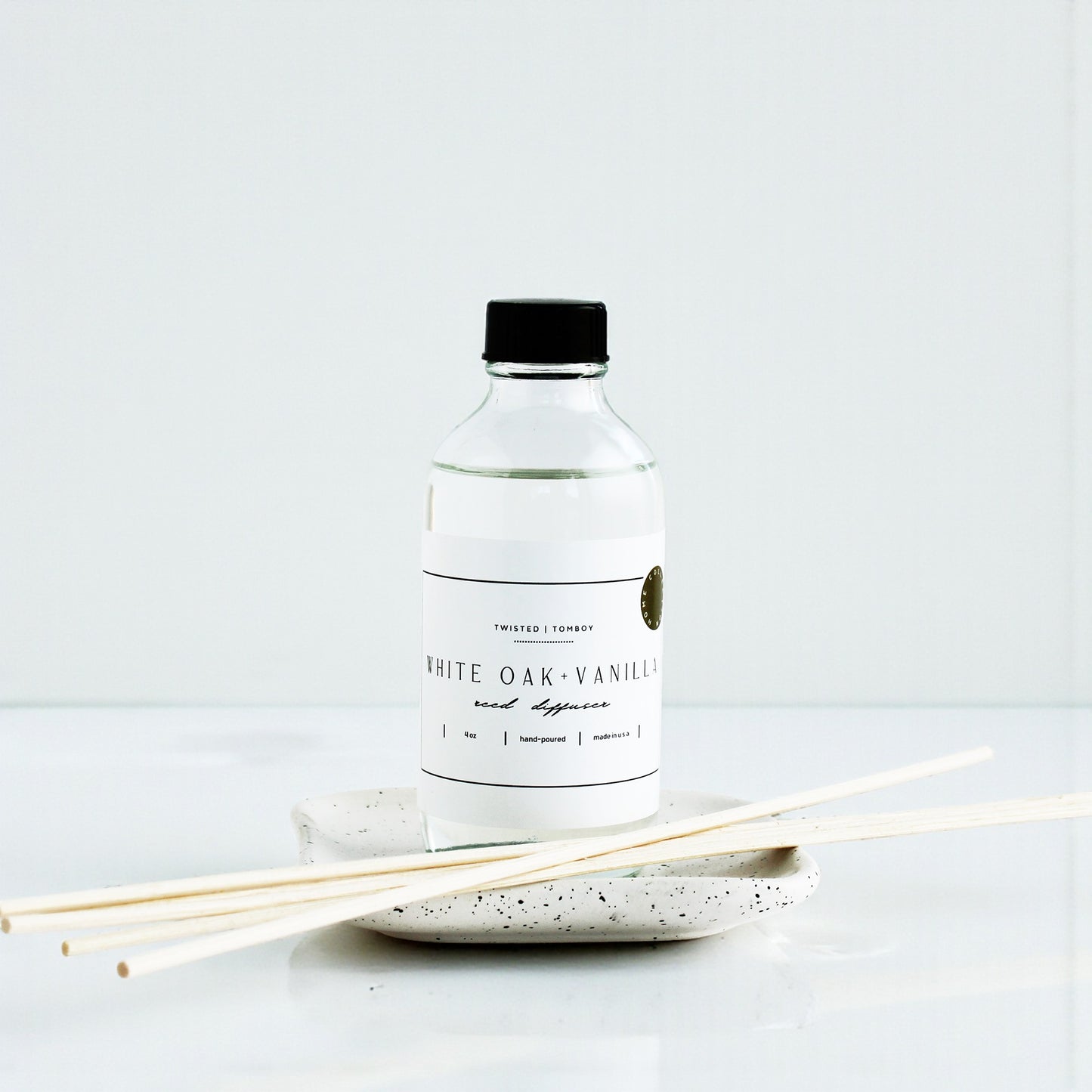 White oak vanilla diffuser bottle with reeds on a white background
