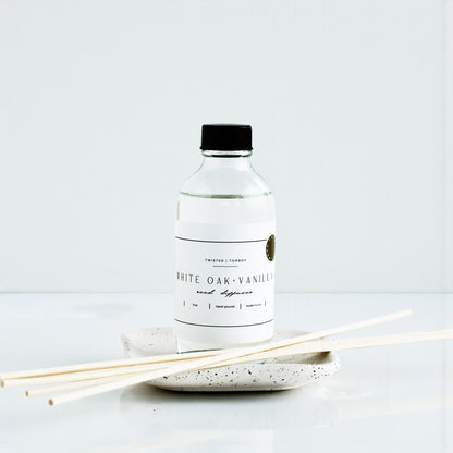 White oak vanilla diffuser bottle with reeds on a white background