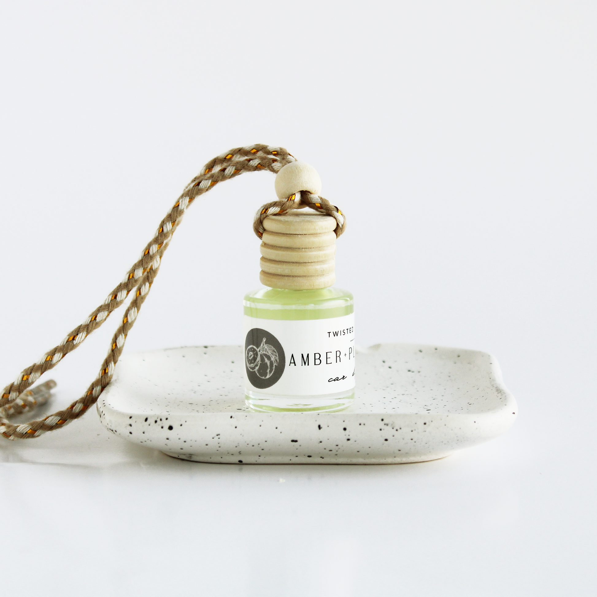 Car diffuser Amber+Plum+Vanilla sitting on small dish