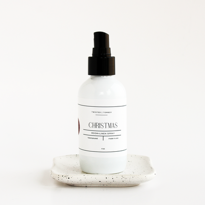 White spray bottle labeled 'Christmas' on a speckled ceramic plate with a white background