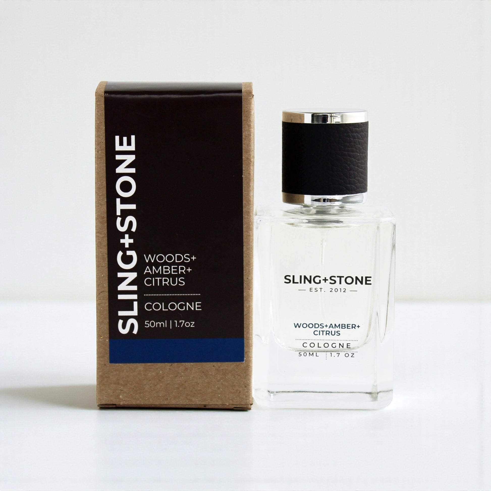 FOR HIM | COLOGNE in a clear bottle with a black cap, featuring a box labeled WOODS+AMBER+CITRUS.